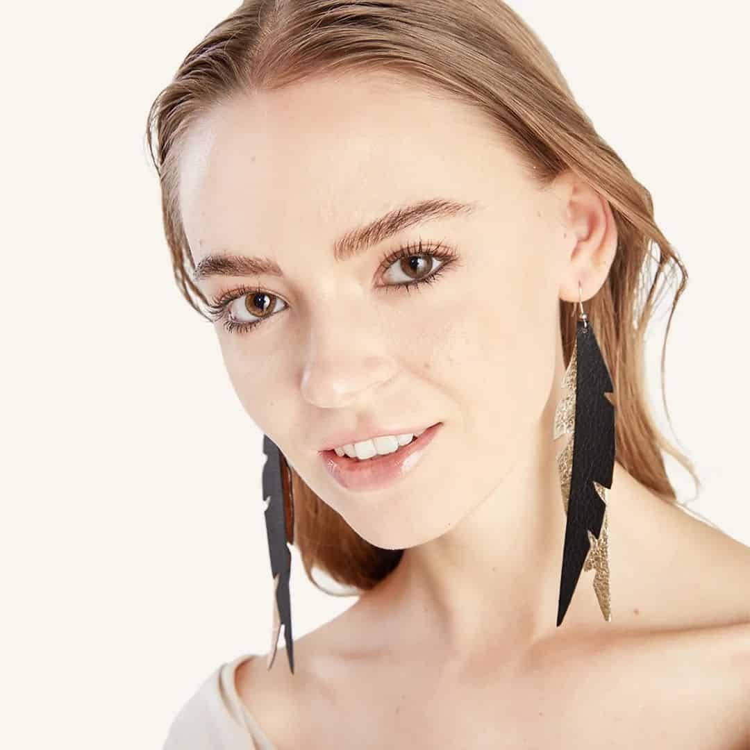 Ruusukullan ja mustan väriset Feathers Glam korvakorut mallin päällä